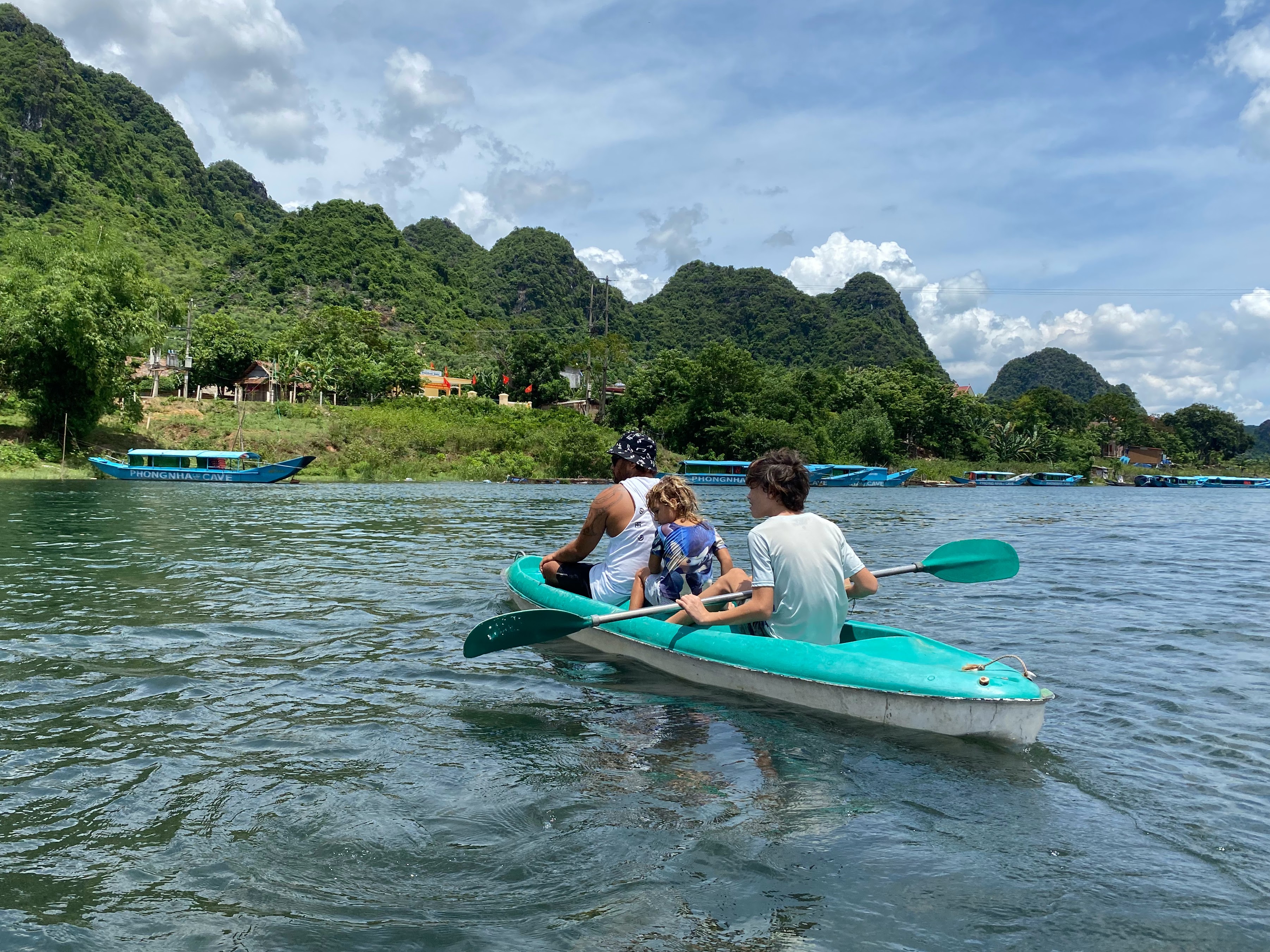 Family kayaking on a calm river surrounded by lush green mountains in Vietnam