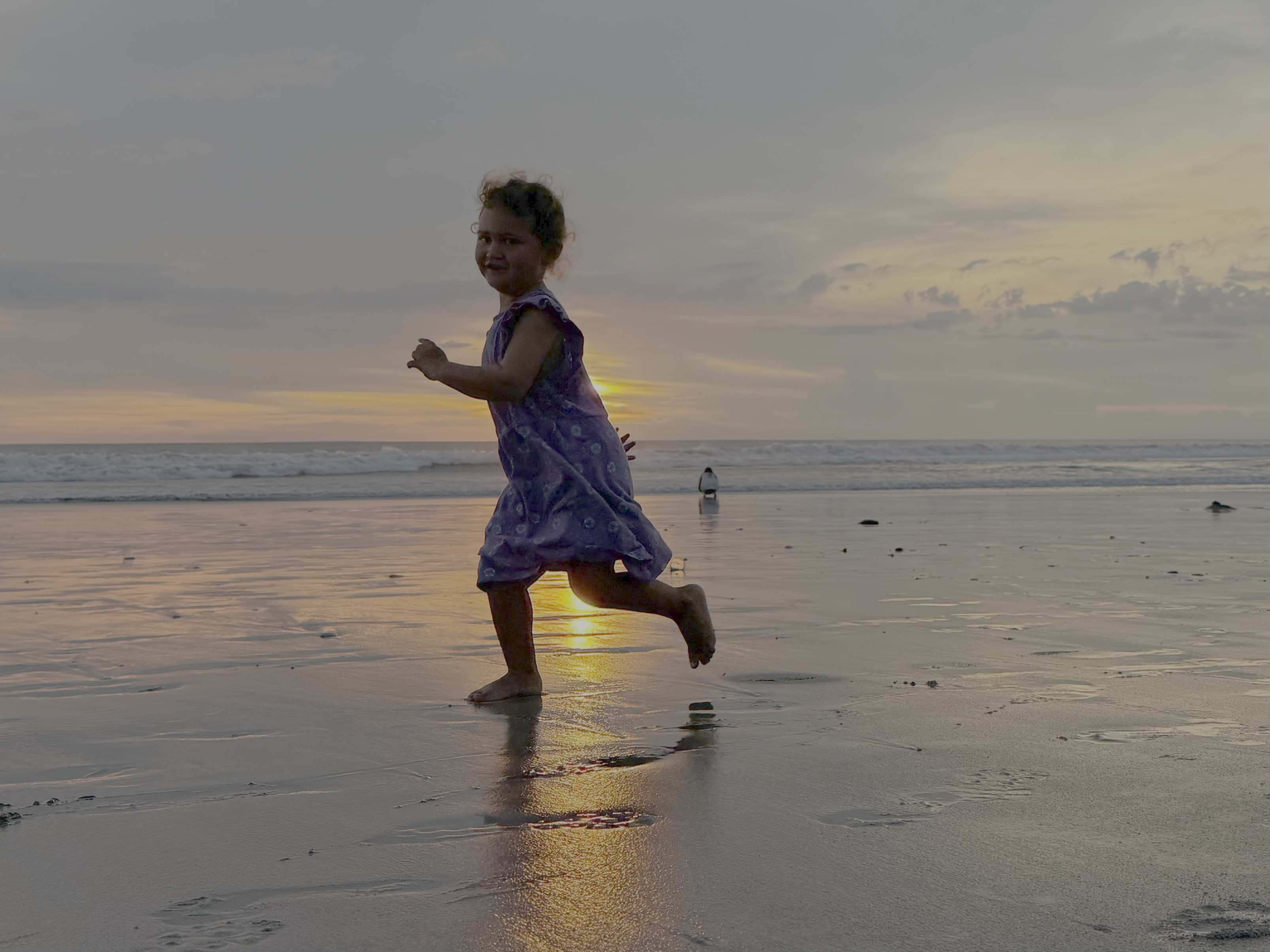 Child running on a beach at sunset, representing family travel and remote work freedom
