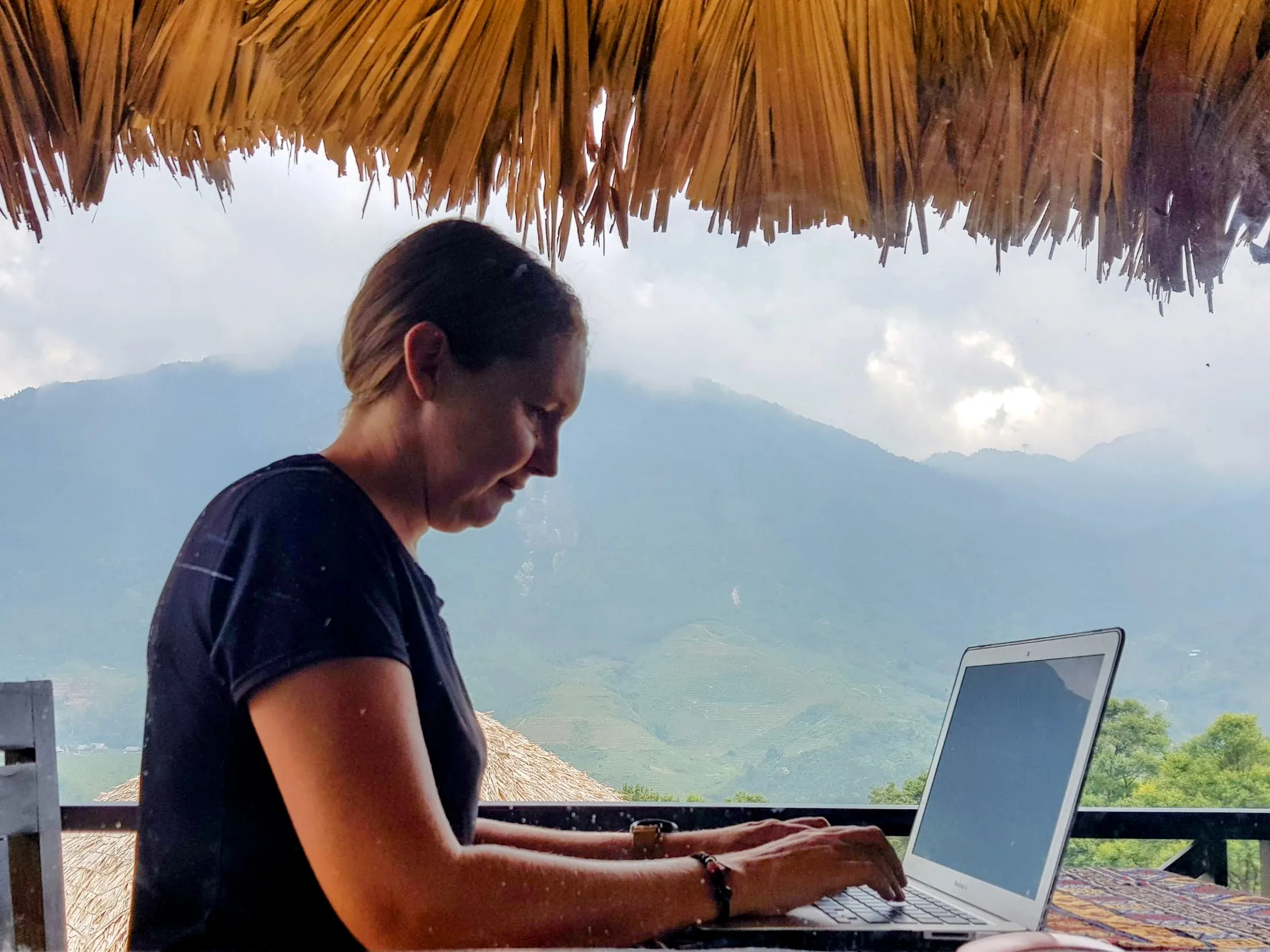 Melissa working on laptop outdoors with mountain view, representing location independent entrepreneurship